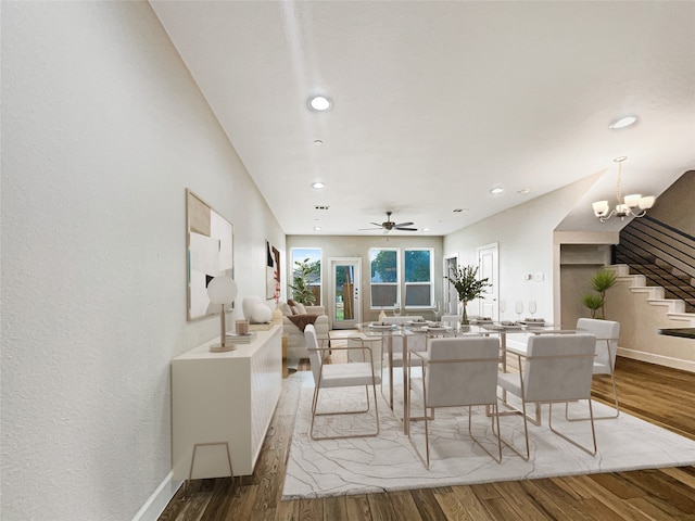 dining space with ceiling fan with notable chandelier and hardwood / wood-style floors