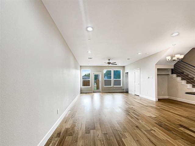 unfurnished living room featuring hardwood / wood-style flooring and ceiling fan with notable chandelier