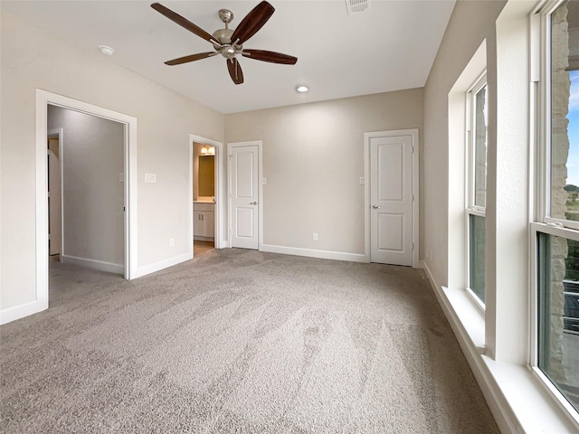 unfurnished bedroom featuring light carpet, connected bathroom, and ceiling fan