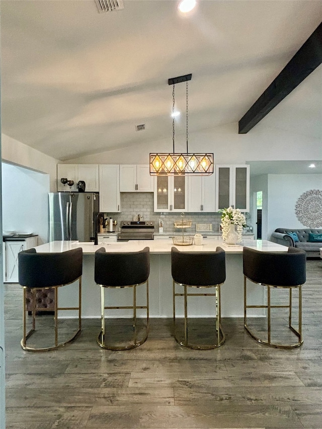 kitchen with appliances with stainless steel finishes, white cabinetry, lofted ceiling with beams, and dark wood-type flooring