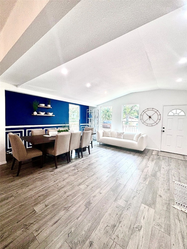 living room with hardwood / wood-style flooring, a textured ceiling, and lofted ceiling