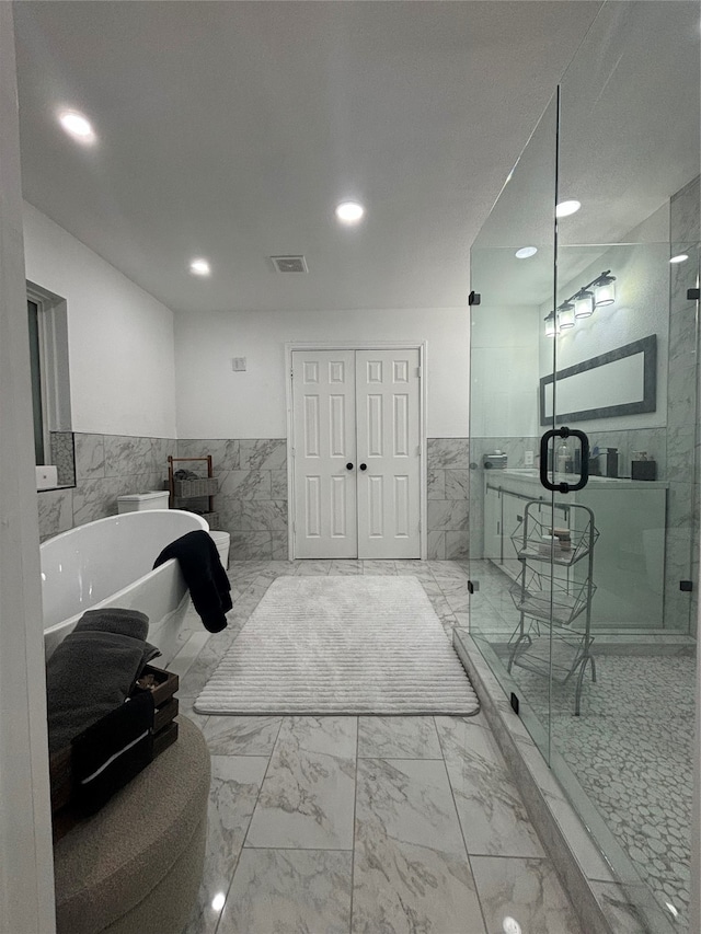 bathroom featuring tile walls and separate shower and tub