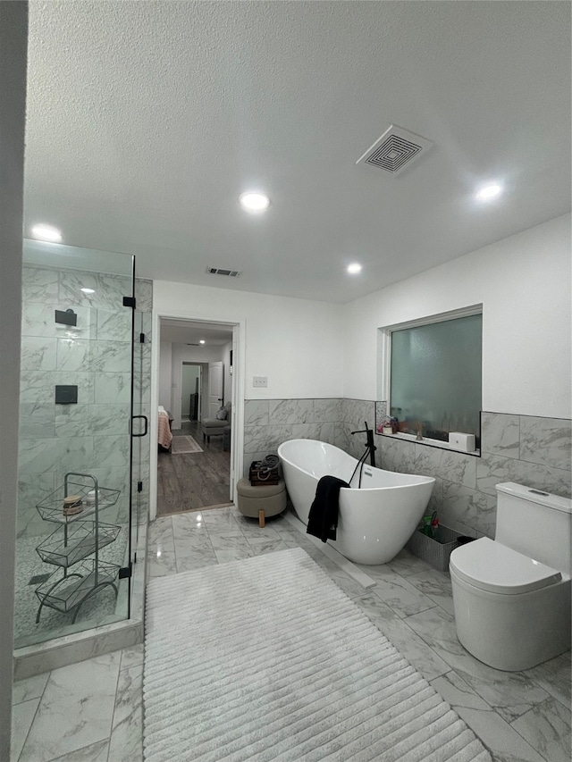 bathroom featuring tile walls, independent shower and bath, a textured ceiling, and toilet