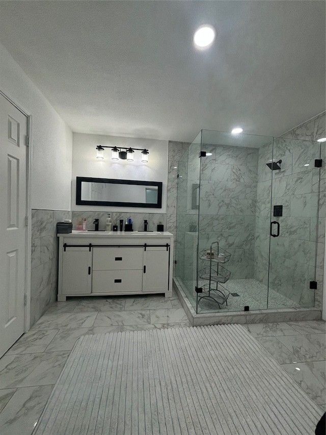 bathroom with a shower with door, vanity, a textured ceiling, and tile walls