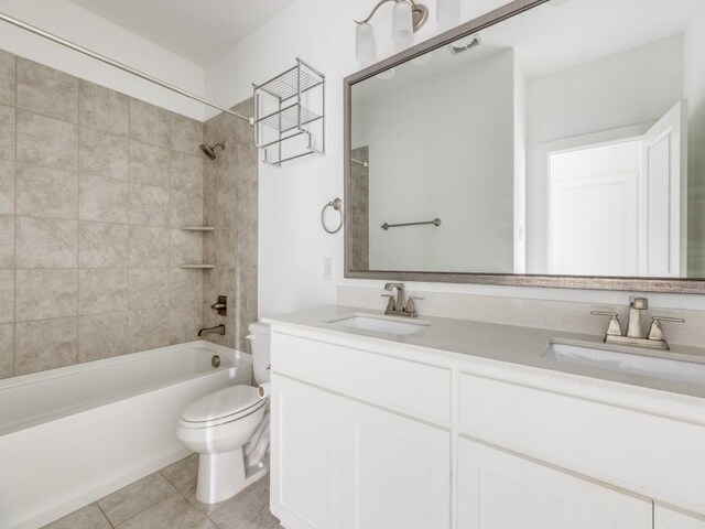 full bathroom with tiled shower / bath combo, toilet, tile patterned floors, and dual bowl vanity