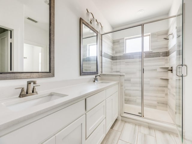 bathroom with a shower with shower door, tile patterned floors, and dual bowl vanity