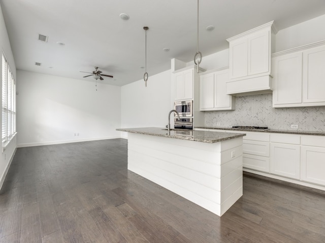 kitchen with stone counters, stainless steel appliances, white cabinets, dark wood-type flooring, and ceiling fan