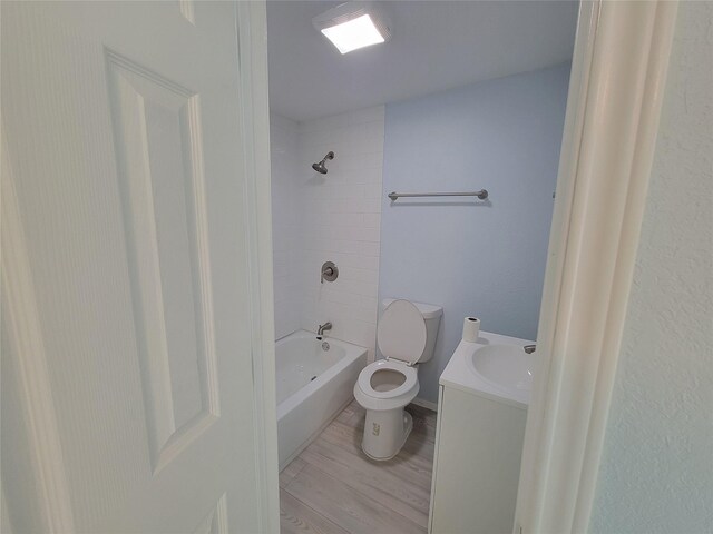 full bathroom with hardwood / wood-style floors, vanity, tiled shower / bath combo, and toilet