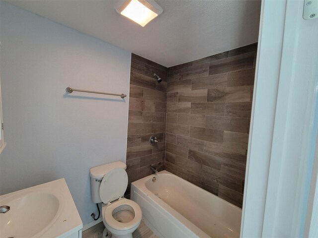 full bathroom featuring vanity, a textured ceiling, tiled shower / bath combo, and toilet