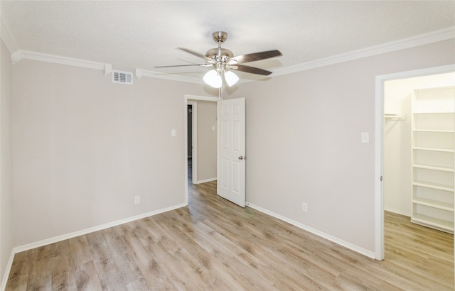 unfurnished bedroom featuring a spacious closet, ceiling fan, ornamental molding, a closet, and light wood-type flooring