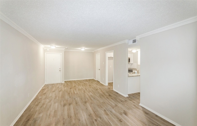 empty room featuring light hardwood / wood-style floors, ornamental molding, and a textured ceiling