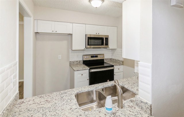 kitchen featuring white cabinets, backsplash, stainless steel appliances, and sink