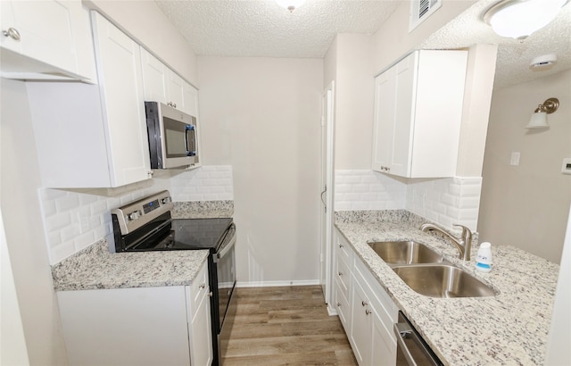 kitchen with white cabinets, appliances with stainless steel finishes, decorative backsplash, and sink