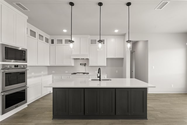 kitchen featuring white cabinets, appliances with stainless steel finishes, an island with sink, and sink