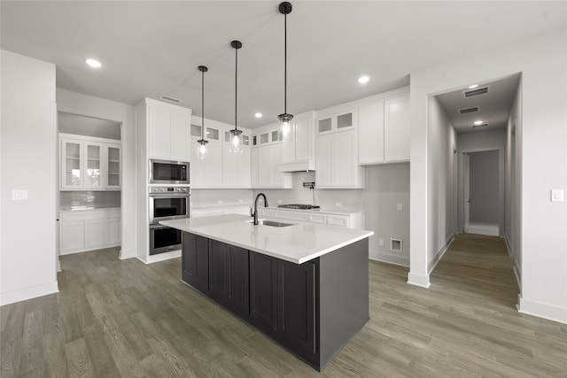 kitchen with stainless steel appliances, sink, dark wood-type flooring, a center island with sink, and white cabinets