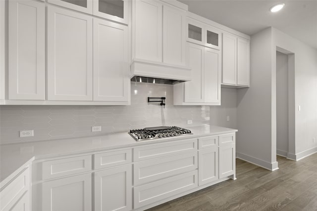 kitchen featuring backsplash, custom range hood, white cabinetry, stainless steel gas cooktop, and dark hardwood / wood-style floors