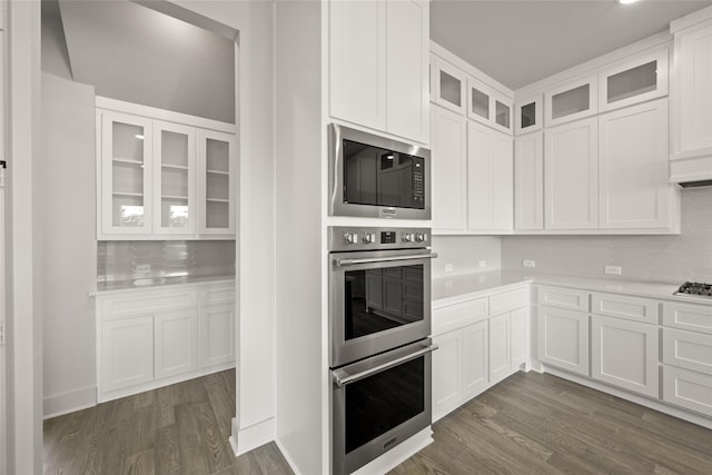 kitchen featuring appliances with stainless steel finishes, tasteful backsplash, dark wood-type flooring, and white cabinets