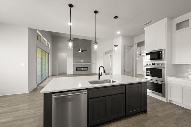 kitchen featuring a kitchen island with sink, hardwood / wood-style floors, stainless steel appliances, sink, and white cabinets