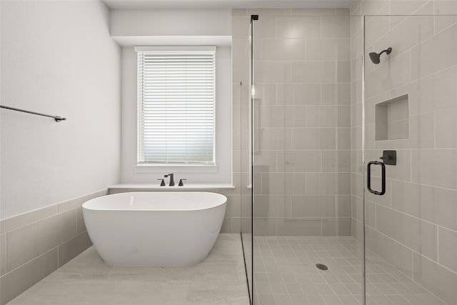 bathroom featuring tile walls and independent shower and bath