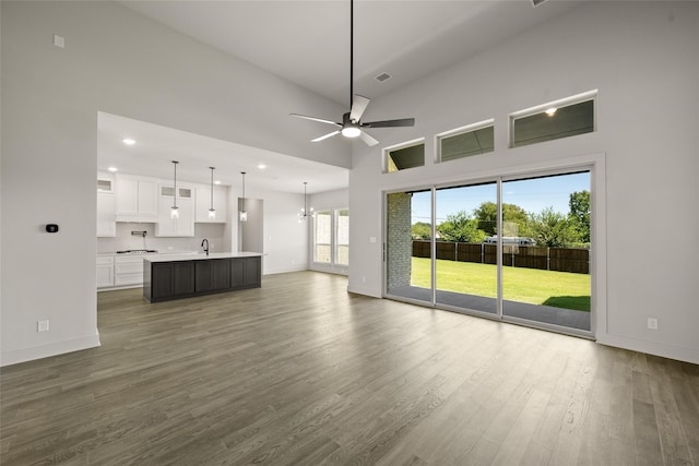 unfurnished living room with ceiling fan, dark hardwood / wood-style floors, sink, and a towering ceiling