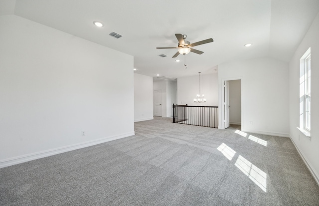 carpeted spare room featuring lofted ceiling and ceiling fan with notable chandelier