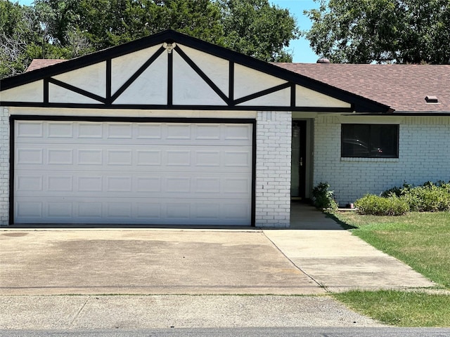 tudor-style house featuring a garage, concrete driveway, and brick siding