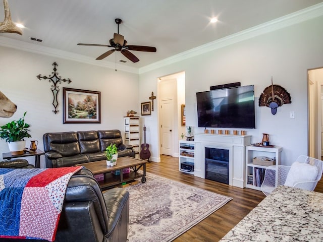 living room with dark wood-type flooring, ceiling fan, and ornamental molding