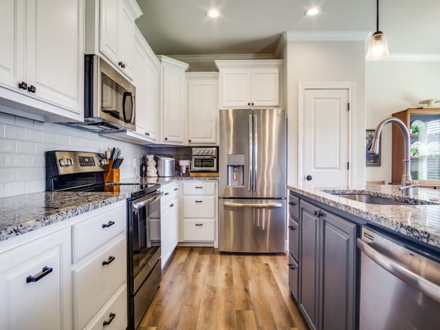 kitchen featuring appliances with stainless steel finishes, light hardwood / wood-style flooring, white cabinets, decorative backsplash, and crown molding