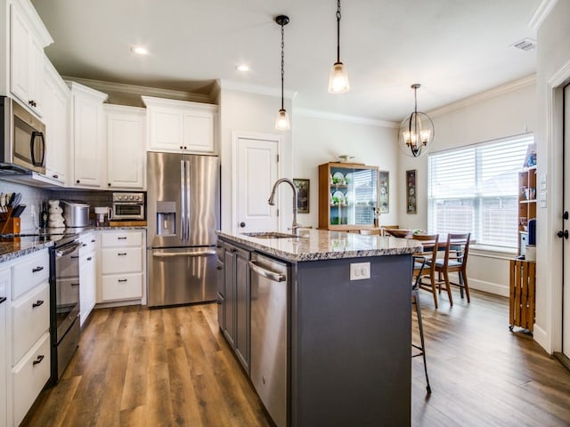 kitchen with appliances with stainless steel finishes, sink, a kitchen island with sink, white cabinetry, and dark hardwood / wood-style flooring