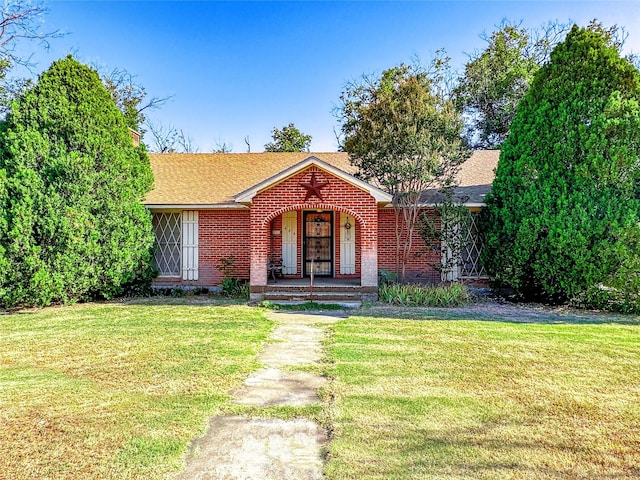 view of front facade with brick siding, a front lawn, and roof with shingles