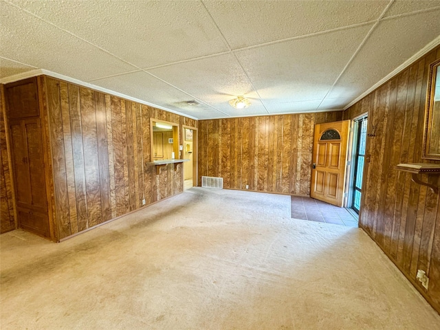 spare room with wooden walls, visible vents, ornamental molding, and light colored carpet