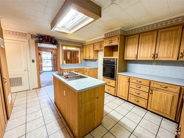 kitchen with a center island, light countertops, stainless steel gas stovetop, visible vents, and black oven