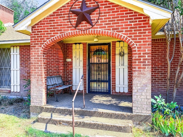 entrance to property with brick siding and roof with shingles