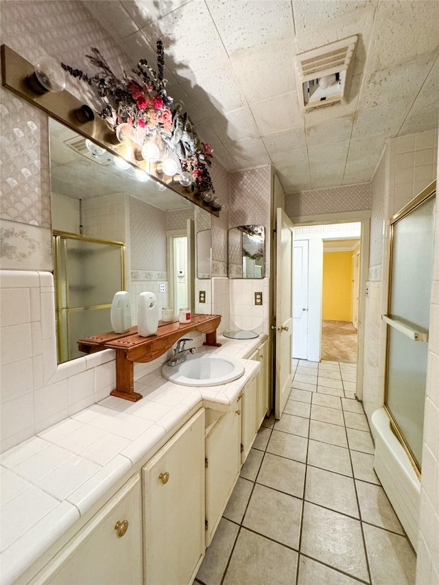 full bath with bath / shower combo with glass door, tile patterned flooring, vanity, and wallpapered walls