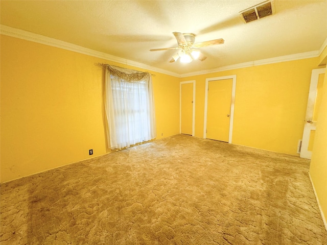 carpeted empty room featuring visible vents, crown molding, a textured ceiling, and ceiling fan