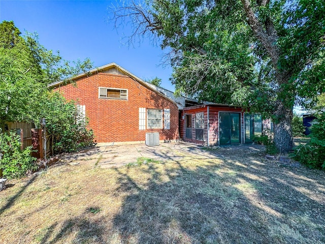 rear view of house with brick siding, cooling unit, and fence