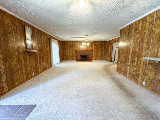 unfurnished living room featuring a brick fireplace, wood walls, and light colored carpet