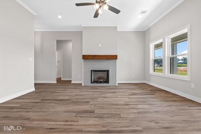 unfurnished living room featuring hardwood / wood-style floors, ceiling fan, ornamental molding, and a tile fireplace