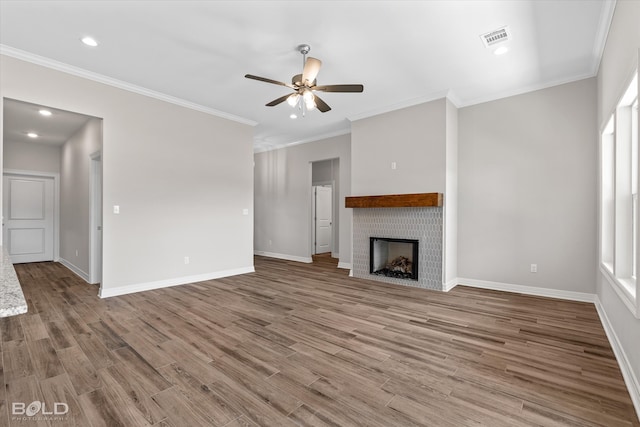 unfurnished living room featuring ceiling fan, ornamental molding, hardwood / wood-style floors, and a brick fireplace