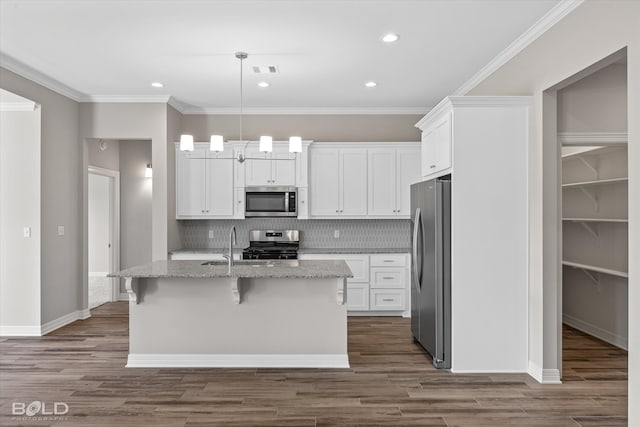 kitchen with a kitchen island with sink, hanging light fixtures, backsplash, stainless steel appliances, and wood-type flooring