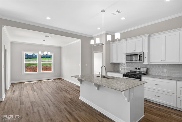 kitchen featuring appliances with stainless steel finishes, white cabinetry, sink, wood-type flooring, and decorative backsplash