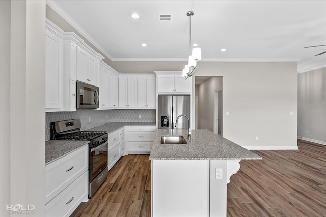 kitchen with tasteful backsplash, light wood-type flooring, appliances with stainless steel finishes, a kitchen island with sink, and sink