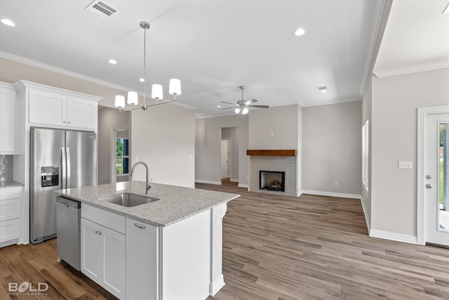 kitchen featuring light wood-type flooring, sink, ceiling fan with notable chandelier, and stainless steel appliances