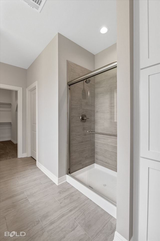 bathroom with a shower with door and tile patterned flooring