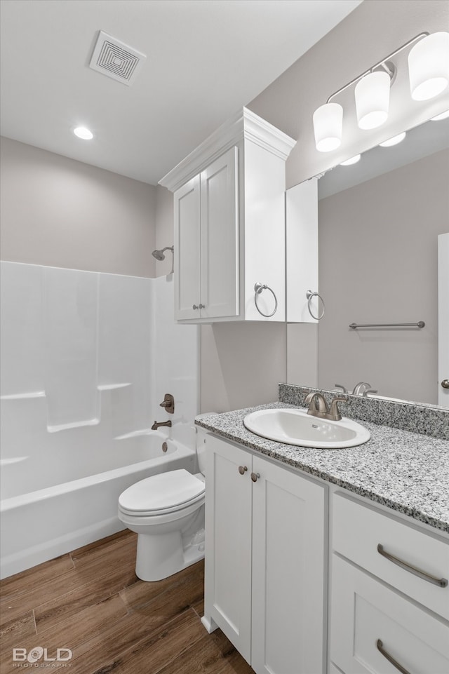 full bathroom featuring wood-type flooring, vanity,  shower combination, and toilet