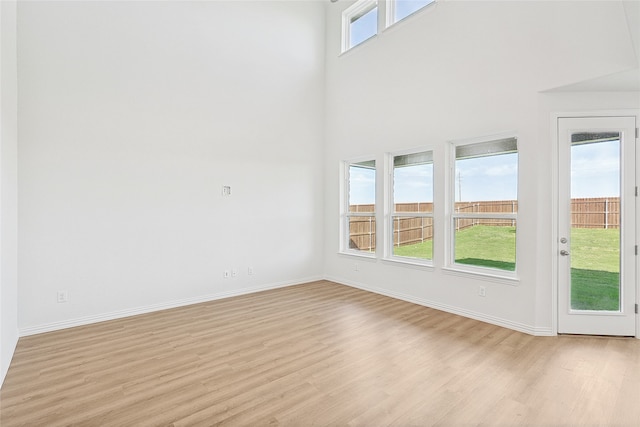 unfurnished room featuring a high ceiling and light hardwood / wood-style flooring