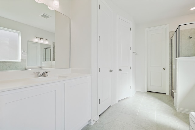 bathroom with a shower with door, vanity, and tile patterned flooring