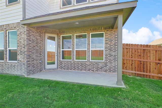 entrance to property featuring a patio area and a lawn