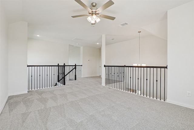 carpeted empty room with lofted ceiling and ceiling fan with notable chandelier