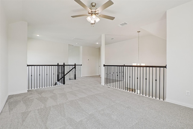 spare room featuring lofted ceiling, baseboards, visible vents, and light colored carpet